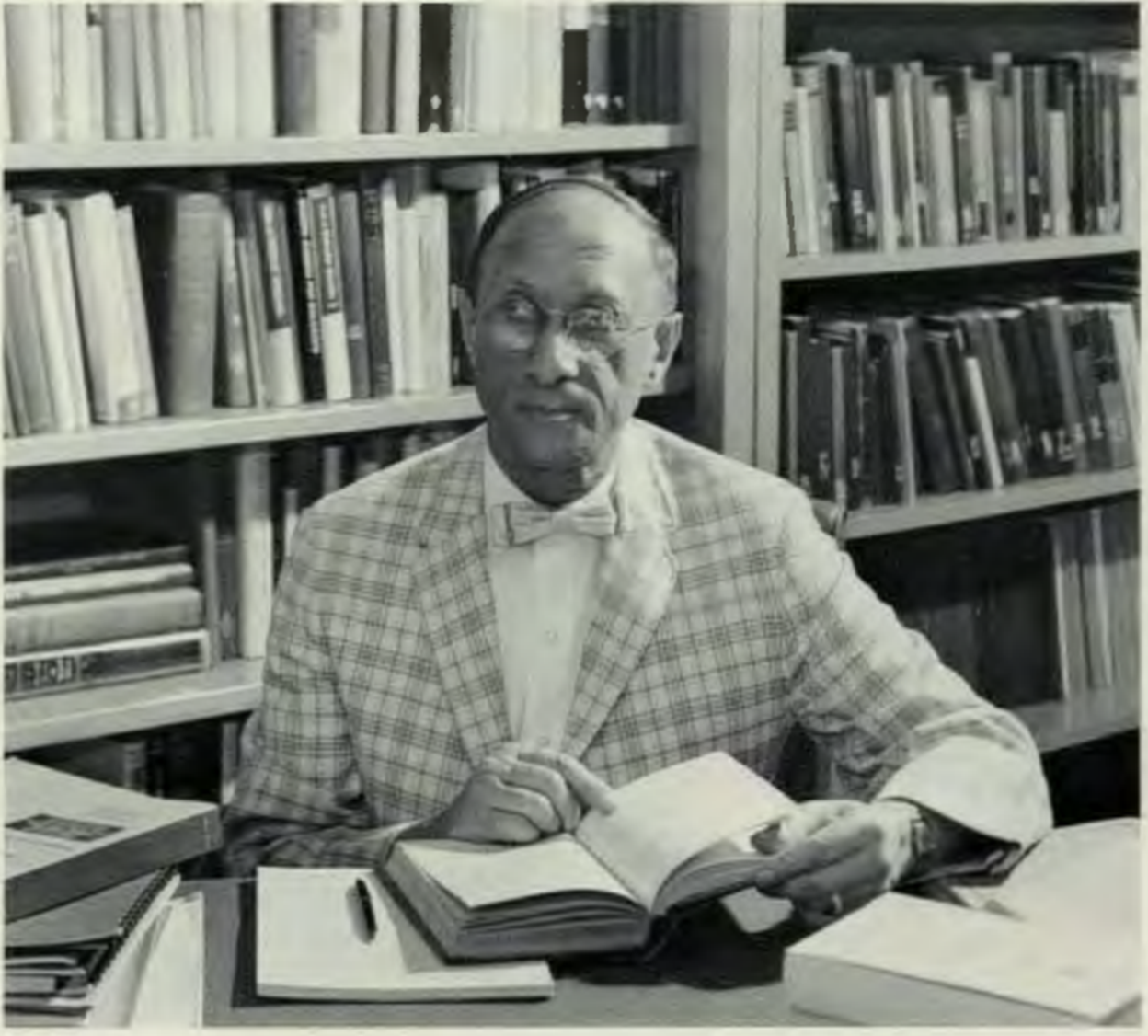 Eugene Guth sitting at a desk with a book
Description automatically generated